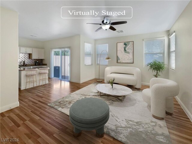 living area with ceiling fan, hardwood / wood-style floors, and sink