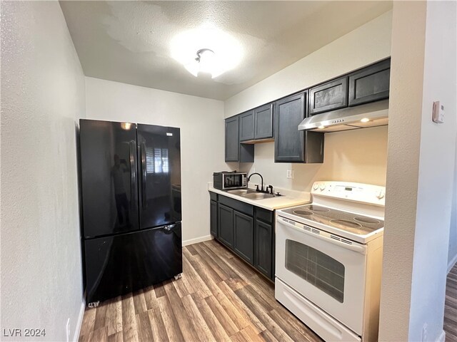 kitchen with electric stove, sink, a textured ceiling, black refrigerator, and hardwood / wood-style flooring