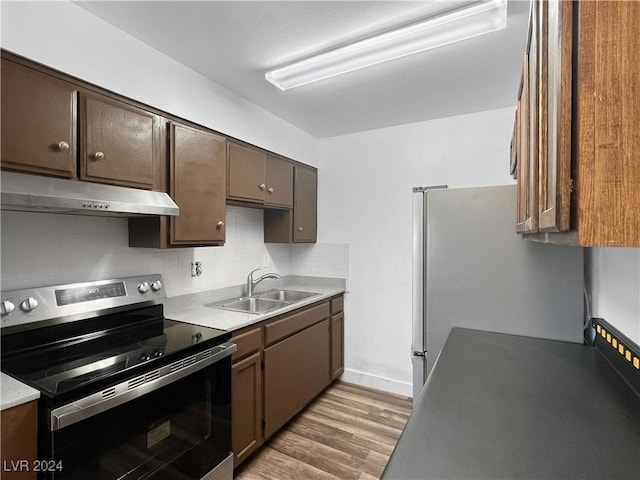 kitchen with appliances with stainless steel finishes, sink, backsplash, light hardwood / wood-style flooring, and dark brown cabinets