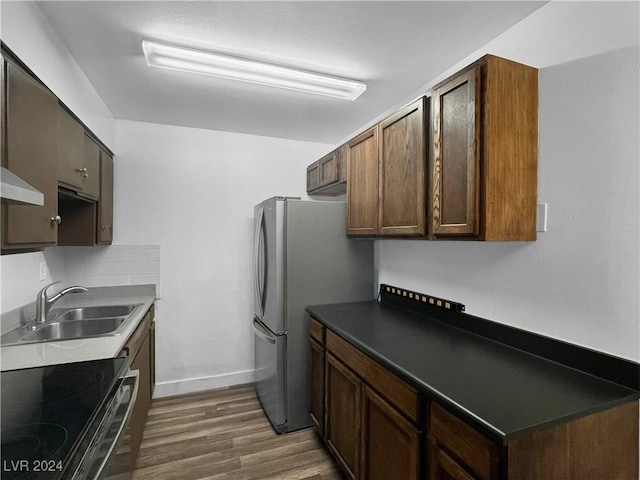 kitchen with dark brown cabinetry, dark hardwood / wood-style flooring, sink, tasteful backsplash, and appliances with stainless steel finishes