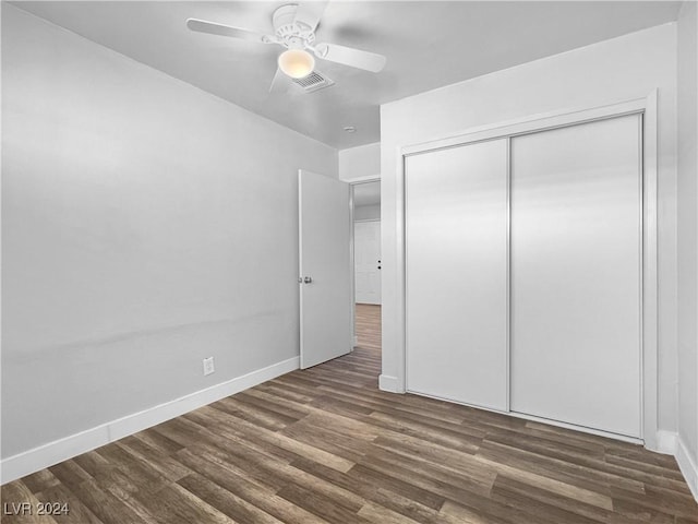 unfurnished bedroom with ceiling fan, a closet, and dark wood-type flooring