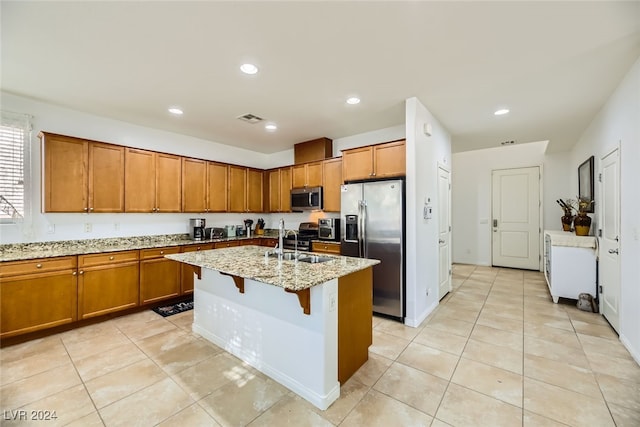 kitchen featuring stainless steel appliances, sink, a center island with sink, light stone countertops, and light tile patterned floors