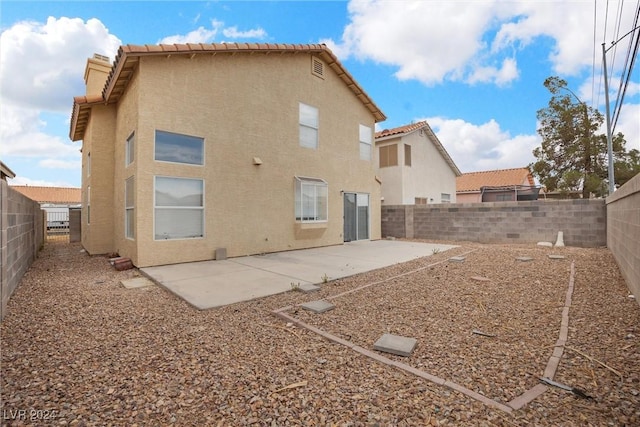 rear view of house with a patio, a tile roof, a fenced backyard, and stucco siding