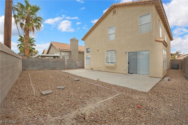 rear view of house with stucco siding, a fenced backyard, a tiled roof, and a patio