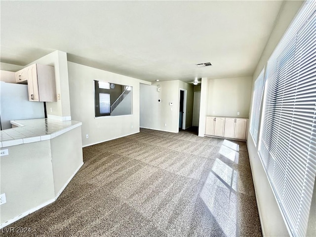 unfurnished living room with dark colored carpet and visible vents