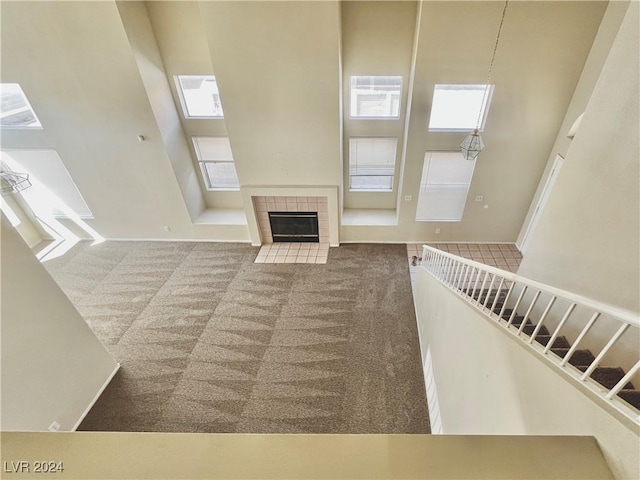 unfurnished living room with carpet floors, a high ceiling, stairway, and a fireplace