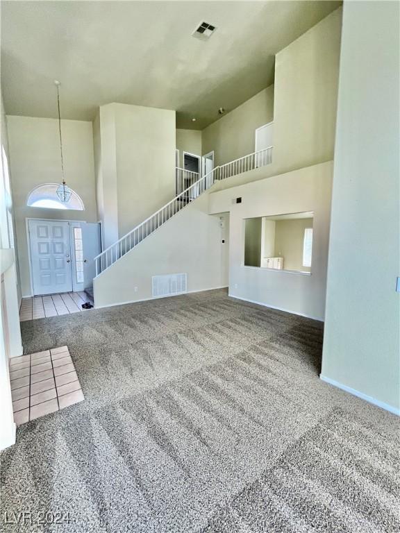 unfurnished living room with a high ceiling, carpet, and visible vents