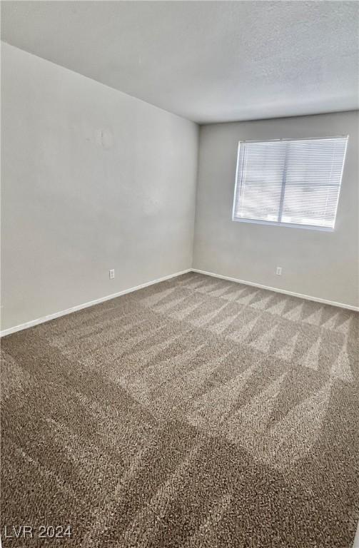 carpeted spare room with baseboards and a textured ceiling