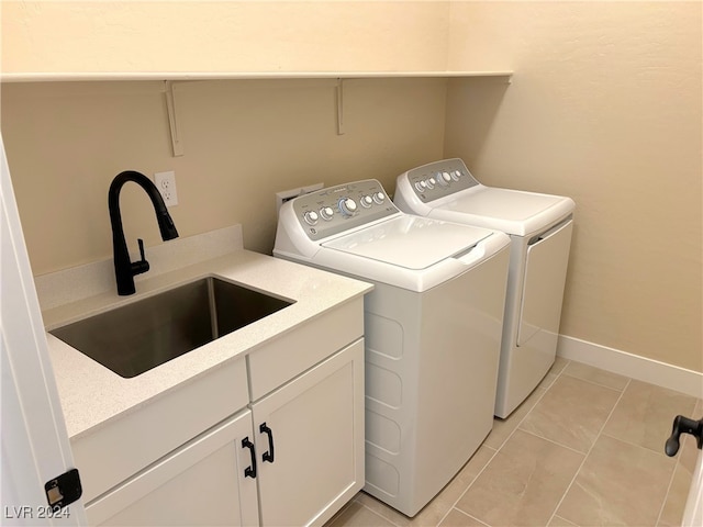 laundry room with cabinets, light tile patterned floors, sink, and washing machine and clothes dryer