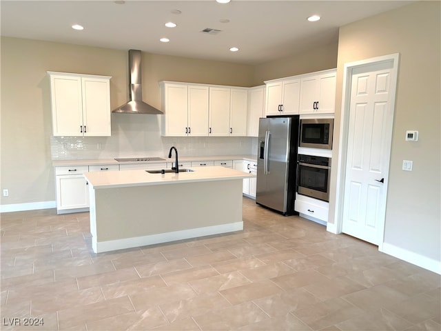 kitchen featuring wall chimney range hood, appliances with stainless steel finishes, sink, and white cabinets