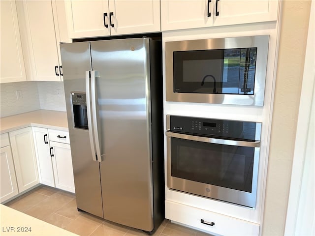 kitchen featuring white cabinets, light tile patterned flooring, appliances with stainless steel finishes, and tasteful backsplash