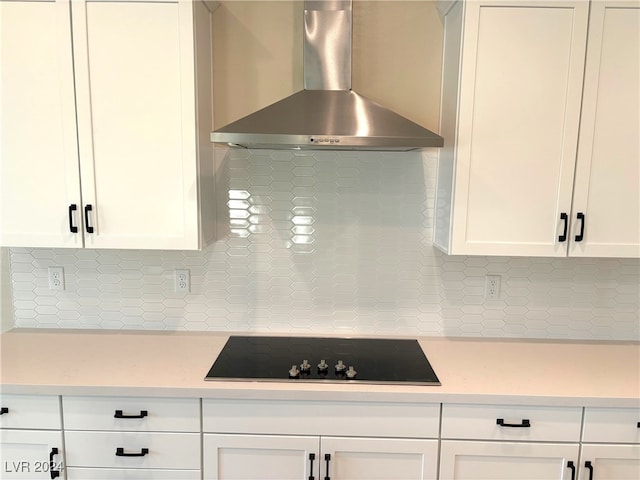 kitchen featuring black electric cooktop, wall chimney exhaust hood, white cabinetry, and backsplash