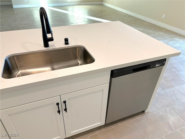 kitchen featuring dishwasher, sink, light stone counters, and white cabinets