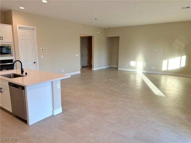 kitchen featuring stainless steel appliances, light tile patterned floors, sink, white cabinets, and a kitchen island with sink