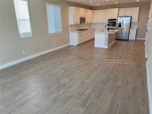 kitchen with white cabinetry, sink, an island with sink, light hardwood / wood-style floors, and appliances with stainless steel finishes