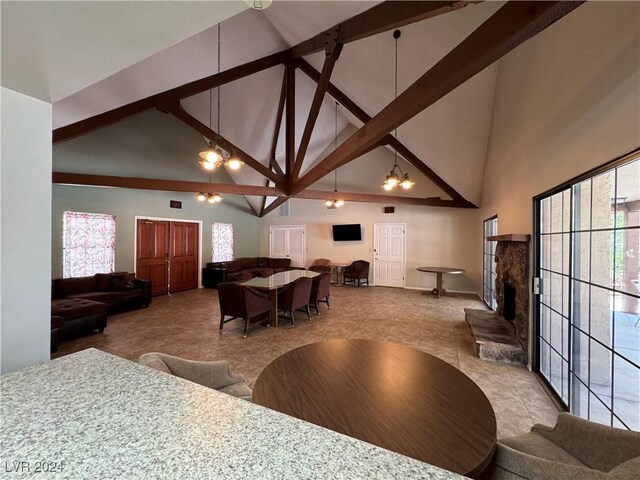 interior space with high vaulted ceiling, beam ceiling, an inviting chandelier, and a healthy amount of sunlight