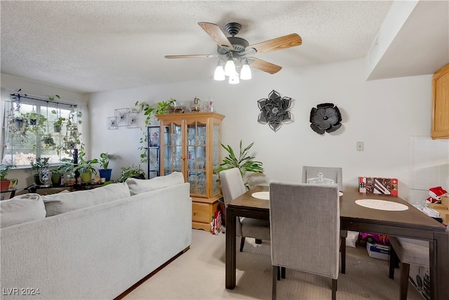 dining area featuring light carpet, a textured ceiling, and ceiling fan