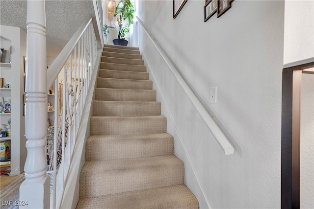 stairway featuring a textured ceiling