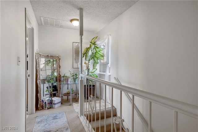 hallway featuring a textured ceiling and light colored carpet