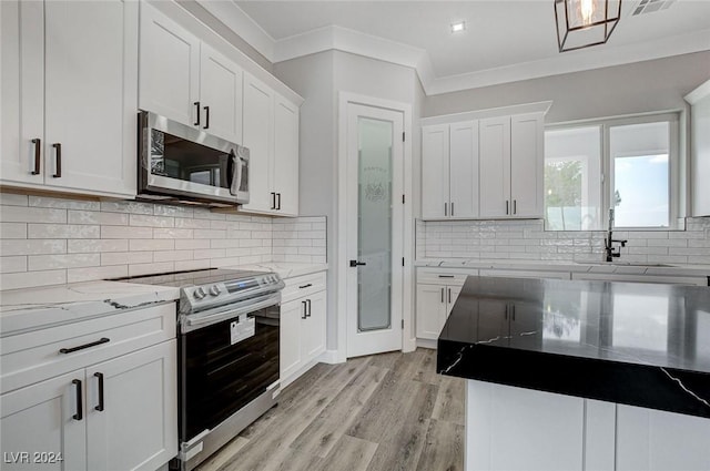 kitchen with appliances with stainless steel finishes, white cabinetry, and crown molding