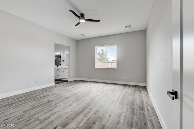 unfurnished bedroom featuring light wood-type flooring, connected bathroom, visible vents, and baseboards