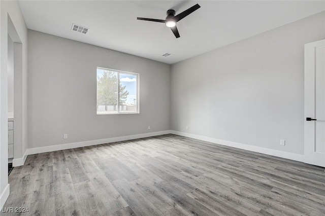 unfurnished room featuring a ceiling fan, light wood-type flooring, visible vents, and baseboards