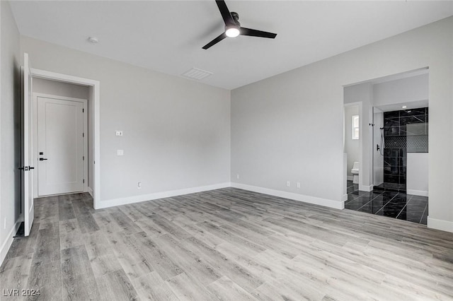 unfurnished bedroom with visible vents, ceiling fan, ensuite bath, wood finished floors, and baseboards