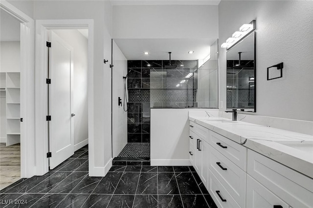 full bath featuring double vanity, marble finish floor, walk in shower, and a sink