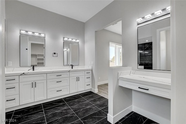 bathroom featuring double vanity, marble finish floor, baseboards, and a sink