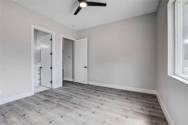 unfurnished bedroom featuring light wood-style floors, baseboards, a ceiling fan, and ensuite bathroom