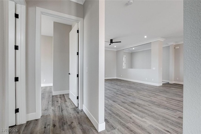 hall featuring baseboards, light wood-type flooring, and crown molding