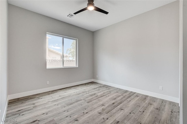 empty room with light wood finished floors, baseboards, visible vents, and ceiling fan