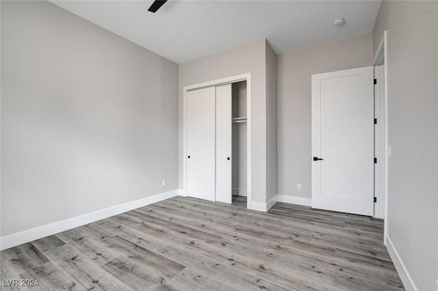 unfurnished bedroom featuring light wood-style floors, a closet, ceiling fan, and baseboards