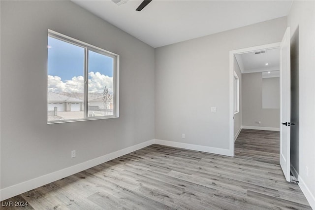 unfurnished room featuring light wood-style floors, visible vents, baseboards, and a ceiling fan