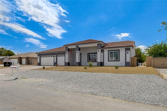 prairie-style house featuring a garage, concrete driveway, fence, and stucco siding