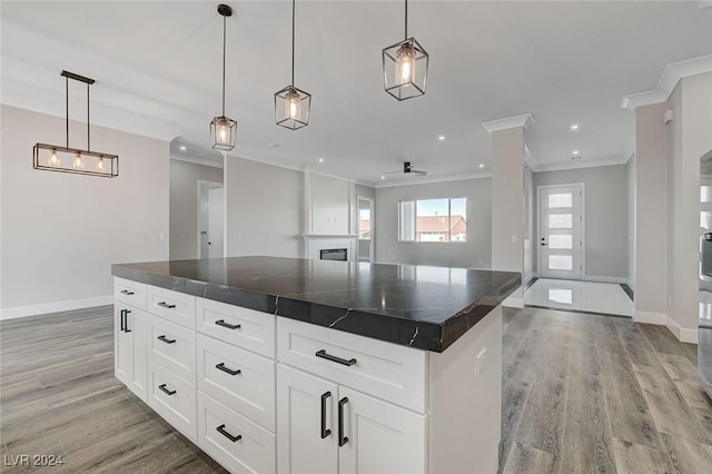 kitchen featuring dark countertops, a kitchen island, open floor plan, and hanging light fixtures