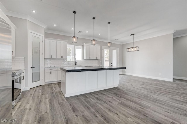 kitchen featuring pendant lighting, electric range, a center island, white cabinets, and light wood-type flooring