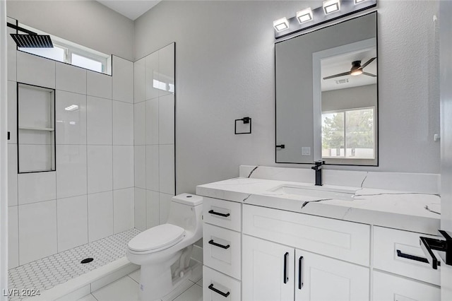 bathroom featuring a healthy amount of sunlight, vanity, toilet, and a tile shower