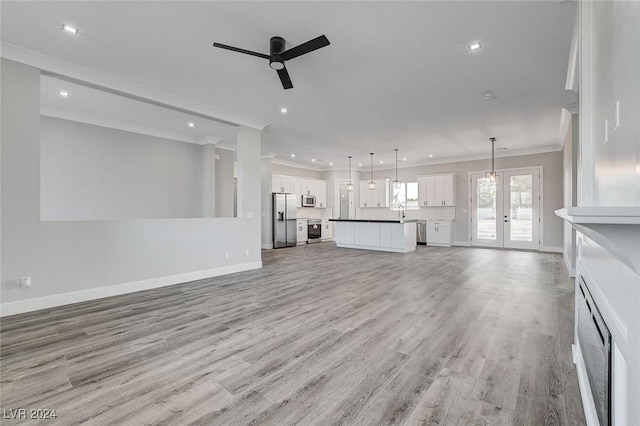 unfurnished living room featuring ornamental molding, french doors, ceiling fan, and light wood-type flooring