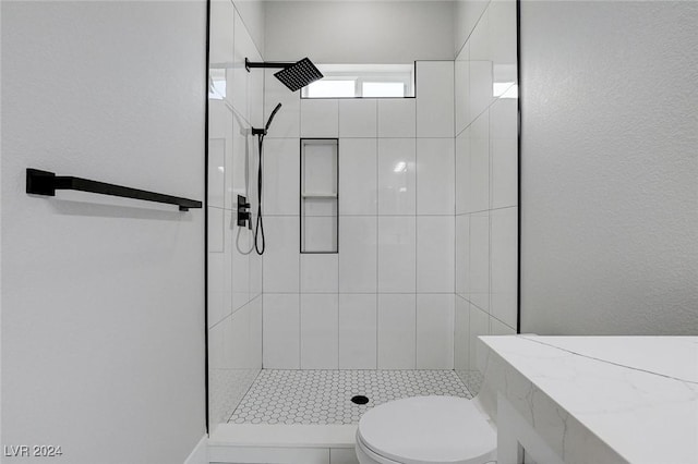 bathroom with a tile shower and toilet