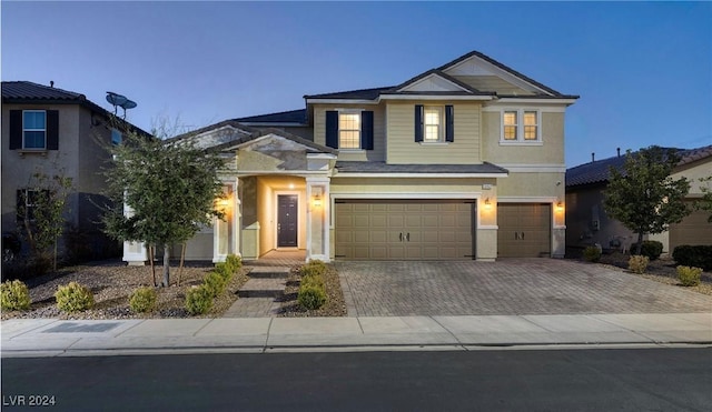 view of front of home with decorative driveway, an attached garage, and stucco siding