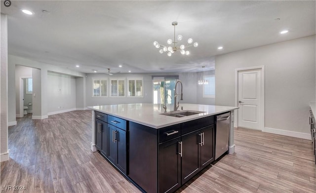 kitchen with a notable chandelier, light wood finished floors, light countertops, a sink, and dishwasher