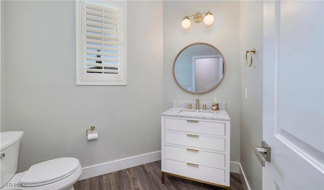 bathroom featuring baseboards, vanity, toilet, and wood finished floors