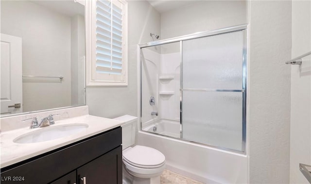 bathroom with enclosed tub / shower combo, vanity, and toilet