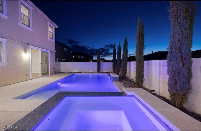 pool at twilight featuring a fenced backyard, a patio, a fenced in pool, and an in ground hot tub