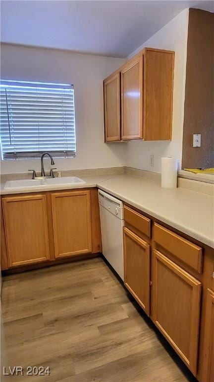 kitchen with light countertops, brown cabinetry, white dishwasher, a sink, and light wood-type flooring