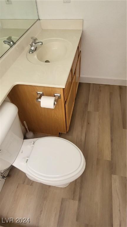 bathroom featuring toilet, wood finished floors, vanity, and baseboards