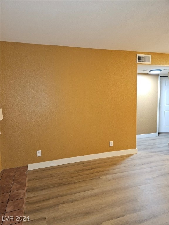 spare room with visible vents, baseboards, and wood finished floors