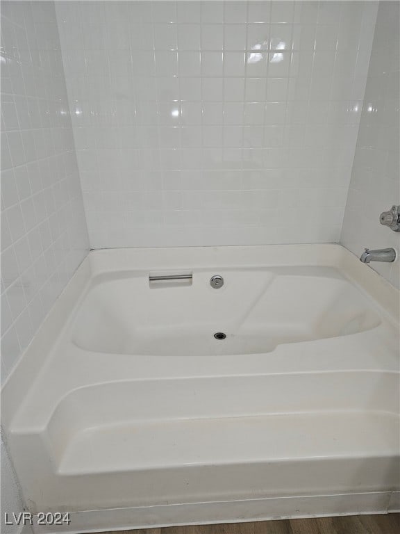 full bath featuring a tub to relax in and wood finished floors