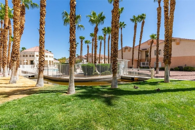 view of community featuring a lawn, fence, and a residential view